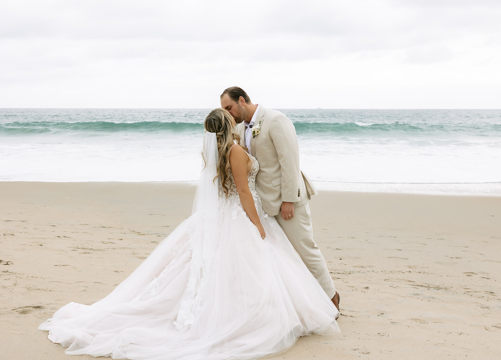 bride and groom kissing at the beach